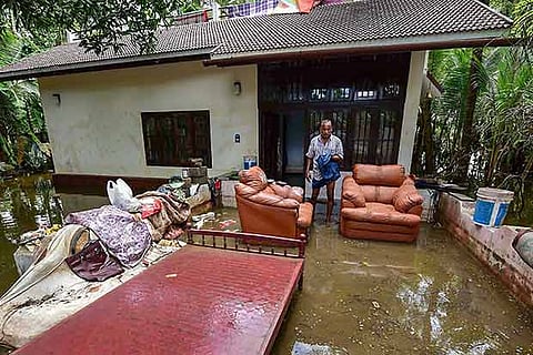 A man cleans up his house after flood water subsided, in Puthenvelikkara near Kochi