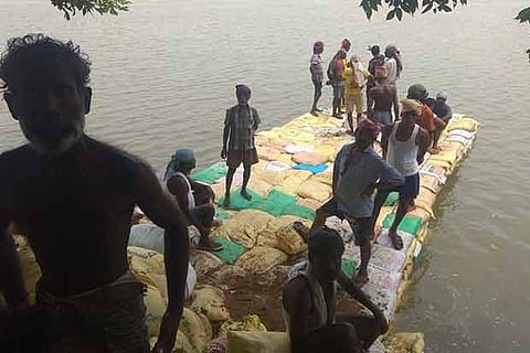 Workers piling up sand bags to arrest the flow near the damaged Kollidam regulator at Mukkombu