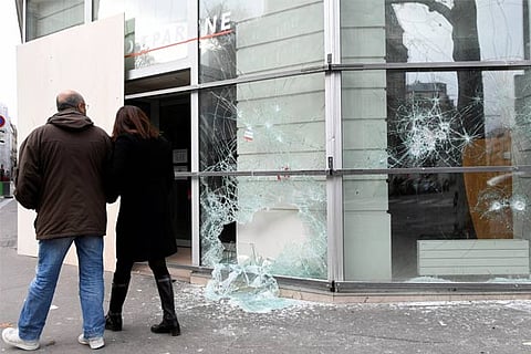 People walk by a vandalized window of bank a day after a nation-wide protest by the Yellow-vests