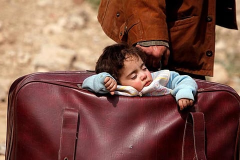 A child sleeps in a bag while travelling in the village of Beit Sawa, eastern Ghouta, Syria