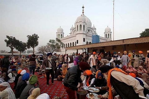 A man serves food to Sikhs from India outside the shrine of Guru Nanak Dev Ji, Kartarpur
