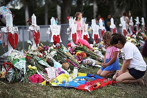 People visit a makeshift memorial setup in front of Marjory Stoneman Douglas High School