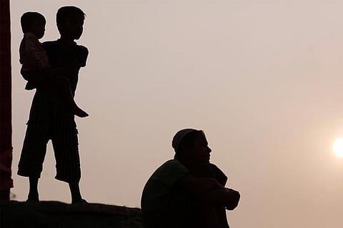 Rohingya refugee children watch a football game during sunset
