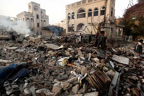 Guards walk on the wreckage of a building destroyed by air strikes in Sanaa, Yemen
