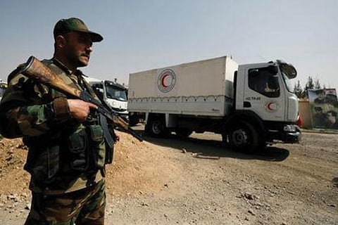 An army soldier is seen securing Syrian Arab Red Crescent trucks carrying aid