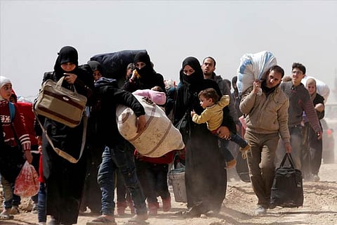 People walk with their belongings as they flee the rebel-held town of Hammouriyeh
