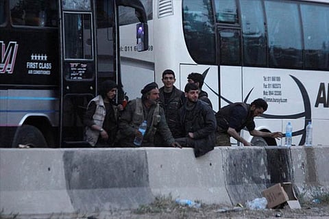Rebels stand together as they wait to be evacuated, outisde Harasta in eastern Ghouta