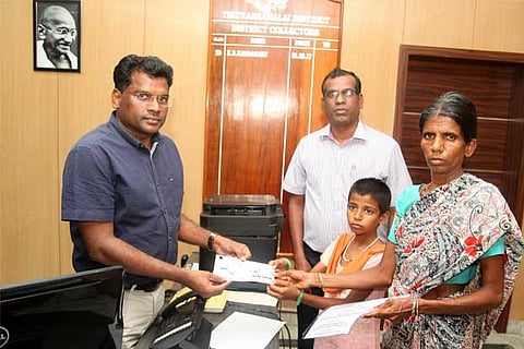 Collector Kandasamy handing over the compensation cheque to Karthika and her mother in Tiruvannamala