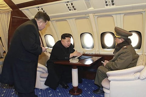 North Korean leader Kim Jong Un (C) talks with officials onboard his personal plane