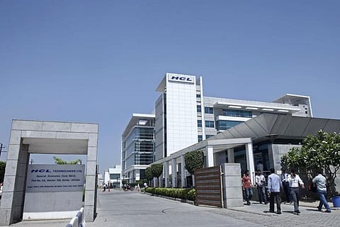 People walk in front of the HCL Technologies Ltd office at Noida, on the outskirts of New Delhi