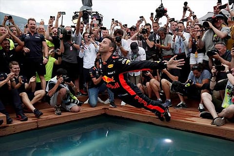 Red Bull's Daniel Ricciardo jumps into a pool as he celebrates winning the race