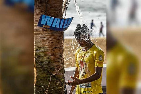 A youth uses an open shower at Kovalam beach after a dip in the sea on Wednesday