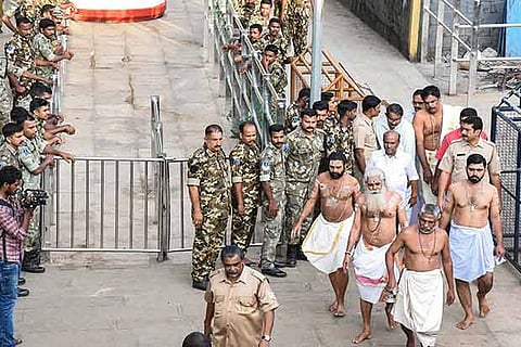 Security personnel stand guard as temple priests walk towards the Sabarimala Temple