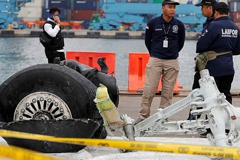 Indonesian forensic policemen stand beside a damaged tire from the the Lion Air flight JT610