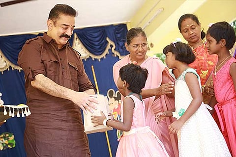 Kamal Haasan gives away a present to a child at the Little Flower Convent School in Chennai