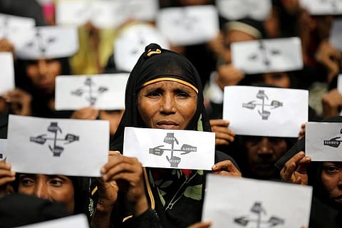 Rohingya refugee women hold placards as they take part in a protest at the Kutupalong refugee camp