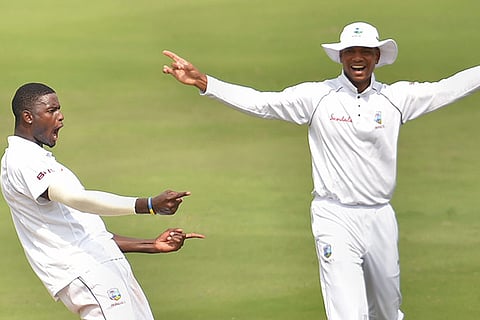 West Indies bowler Jason Holder (L) celebrates the wicket of Indian batsman Virat Kohli