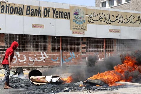 Protesters block a street with burning tires after the Yemeni Riyal has severely plunged