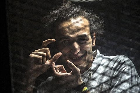 Egyptian photographer Mahmoud Abu Zeid, known as Shawkan, gestures from inside a soundproof glass