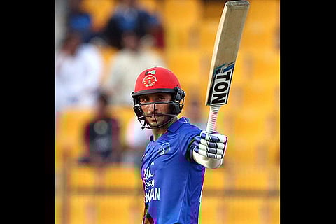 Afghanistan's Rahmat Shah raises his bat to celebrate scoring fifty runs