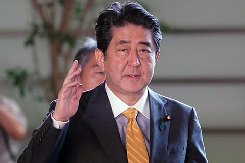 Japanese Prime Minister Shinzo Abe waves to the media upon his arrival at his official residence