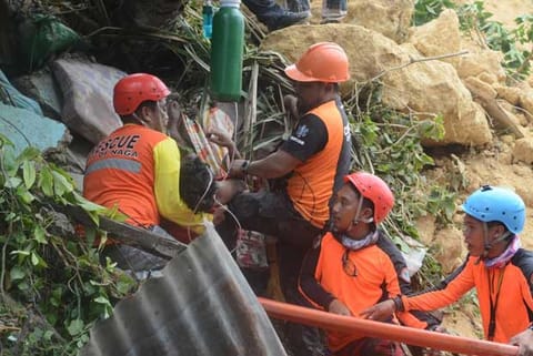 Rescuers pull out a survivor from rubble after a landslide in the City of Naga, Cebu, Philippines