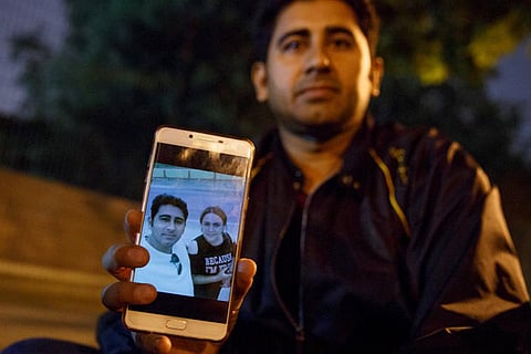Mirza Imran Baig shows a pic of his wife as he sits outside Pakistani embassy, Beijing