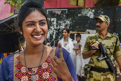 A first-time voter shows her inked finger after casting her vote at a polling station