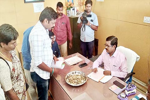 Independent candidate Prabakaran giving Rs 10 coins to file nominations to the election officer in Sulur