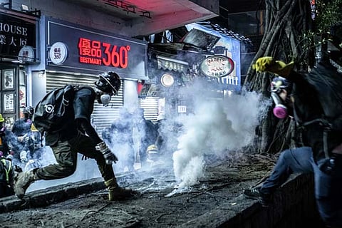 Protesters throw back teargas bombs during clashes with police on Sunday. File: AP