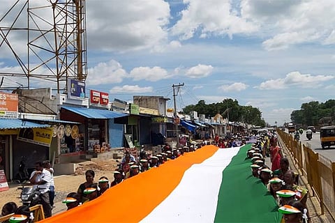 Students carry the 150-ft-long national flag through an arterial road in Ambur town, the Independence Day