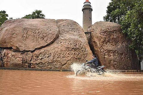 A man rides a motorcycle through a waterlogged road after heavy rains, at the heritage town of Mahabalipuram