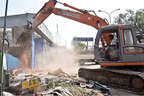Earthmovers demolish houses near the east rampart in Thanjavur on Monday