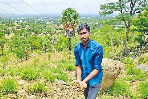 Dinesh Saravanan throws seed balls near a hillock Vellore