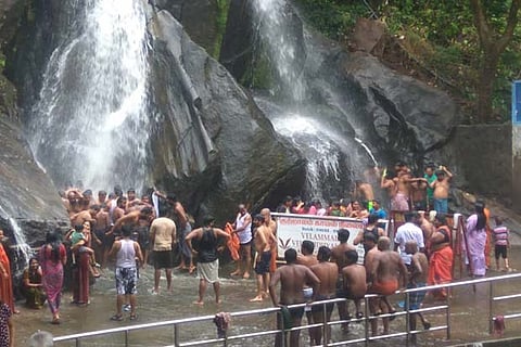 Tourists enjoy the first flow of the season in Courtallam on Monday