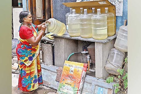 An elderly woman fetches water from a can near her residence, in Chennai on Tuesday