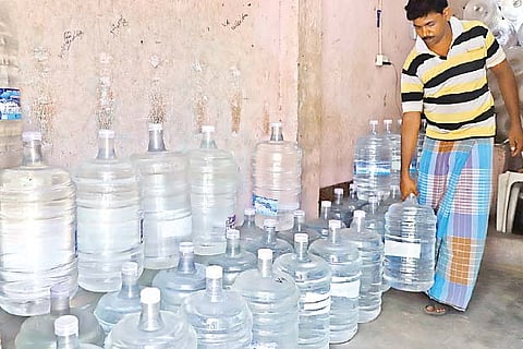 A supplier of treated water cans arranges his stock