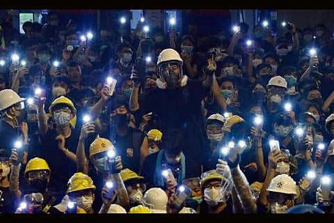 Protesters hold up the mobile phone lights in front of police headquarters in Hong Kong