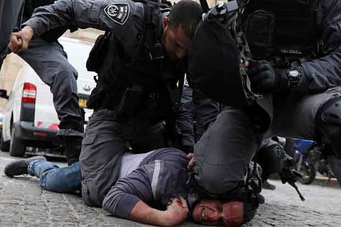 Israeli police officers detain a Palestinian protestor during scuffles