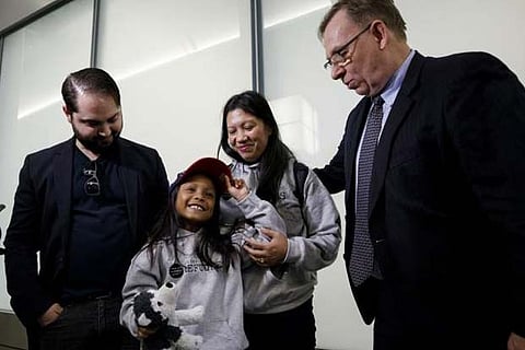 Lawyer Robert Tibbo, right, embraces Vanessa Rodel and her daughter Keana as the pair arrive in Canada