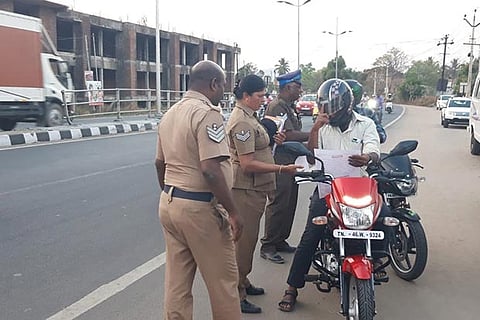 Police personnel distribute handbills to a rider in Thudiyalur on Thursday