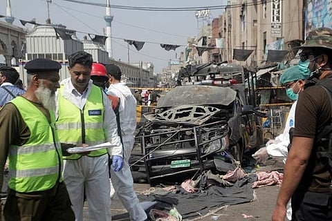Security officials and members of a bomb disposal team survey the blast site in Lahore, Pakistan