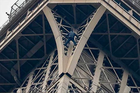A man climbs up to the top of the Eiffel Tower, in Paris, without any protection | AFP