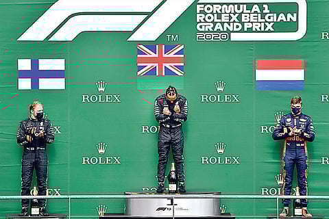 Lewis Hamilton (centre) gestures on the podium