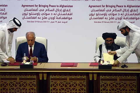 Mullah Abdul Ghani Baradar, the leader of the Taliban delegation, signs an agreement with Zalmay Khalilzad.