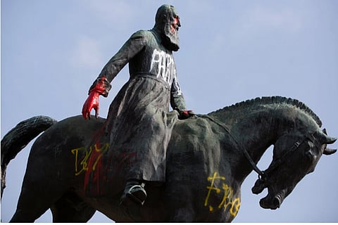 A statue of Belgium King Leopold II is smeared with red paint and graffiti in Brussels