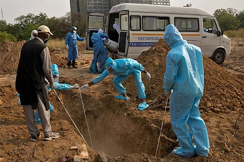 Body of a woman who died from COVID-19, is lowered in a grave as another one is taken out (Reuters)