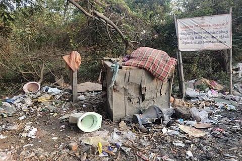 Despite a warning board that says not to dump waste, garbage, including a toilet seat, is discarded