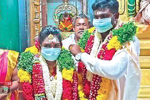 A newly-wed couple with masks after the marriage at a temple in Thoothukudi early on Sunday
