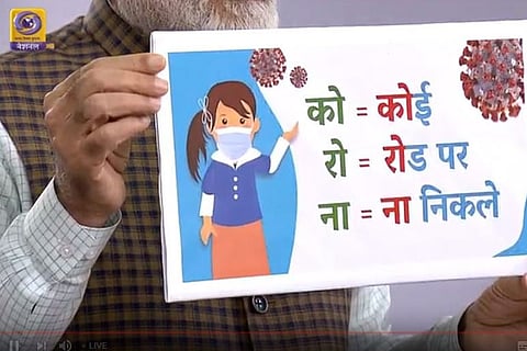 PM Modi displays a poster saying - Corona means 'Koi Road Par Na Nikle' (No one should venture out on streets)